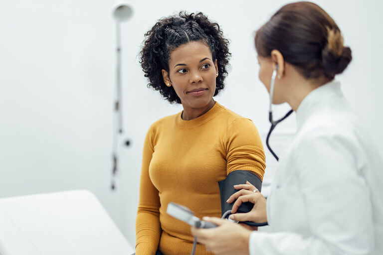 primary care doctor measuring female patient's blood pressure