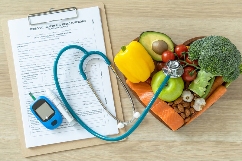stethoscope next to bowl of fruit and vegetables 