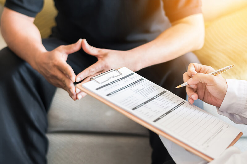 doctor listening to patient and filling out a form